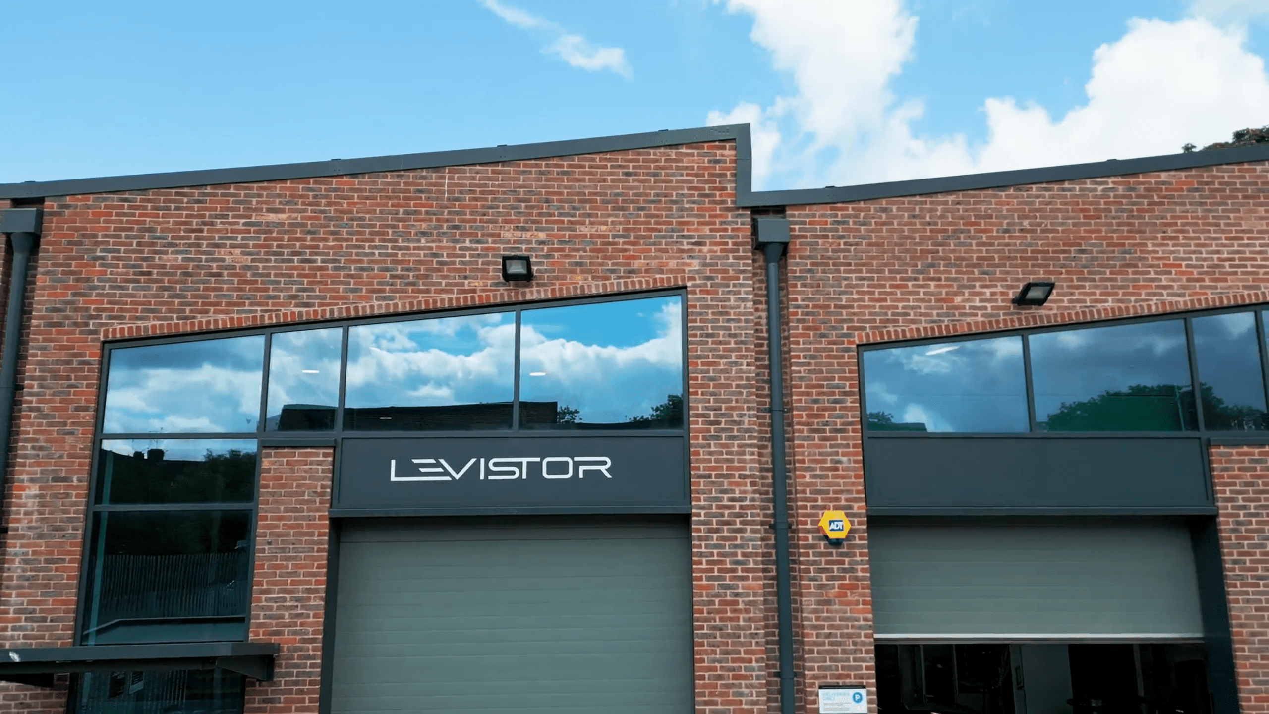 An exterior view of Levistor's factory facilities, featuring warm brick, glass, and futuristic angular architecture.